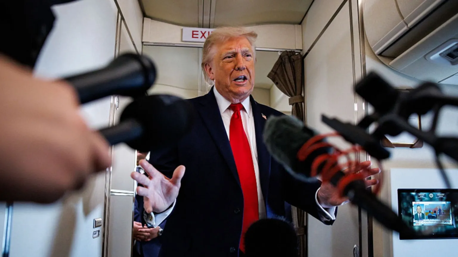 Several microphones point at Donald Trump in Air Force One.